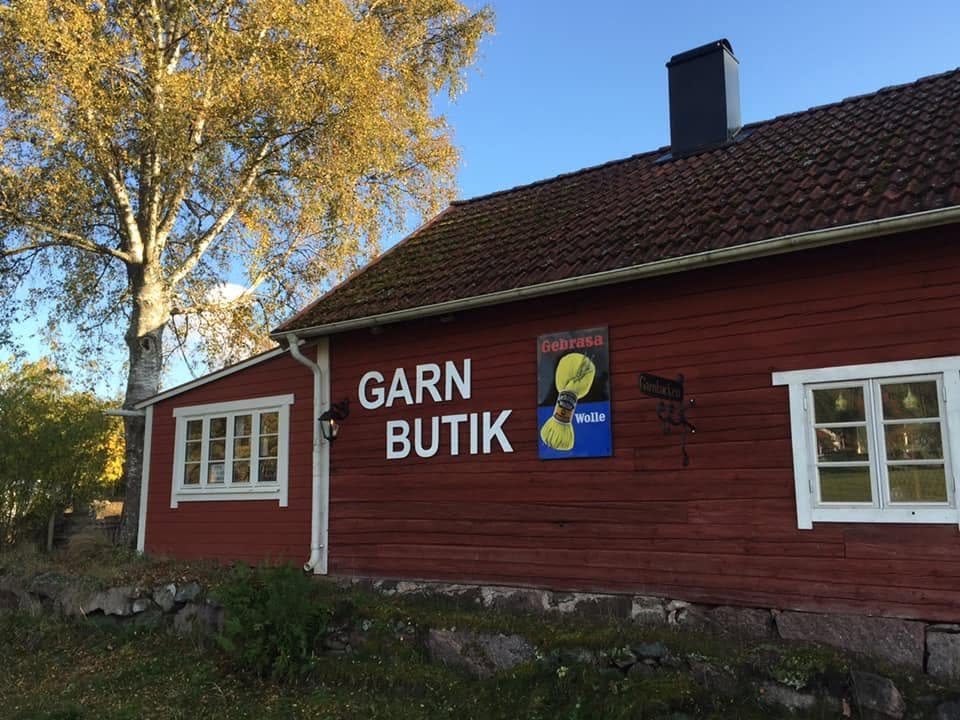 Garnbacken, ett rött torp med skylten Garnbutik, en höstdag med gula björkar