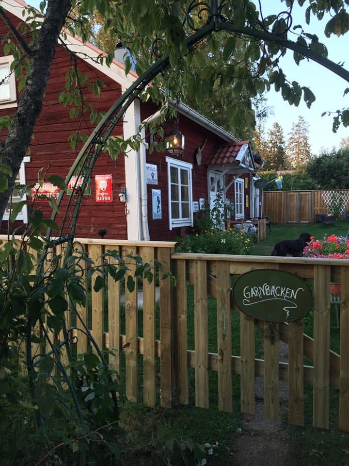 Grinden med skylten Garnbacken framför torpet en sommarkväll